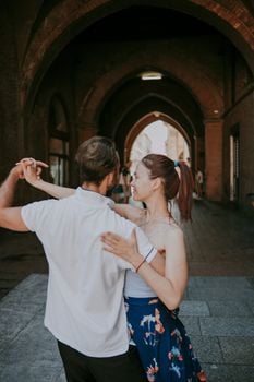 A couple joyfully dances under an urban archway, adding romance and elegance to the city backdrop.