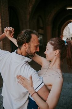 A couple shares an intimate dance in a sunlit archway, embracing love and connection.