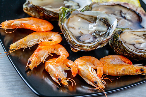 Close Up Food Photo of Fresh Shrimps and Oysters on Black Plate