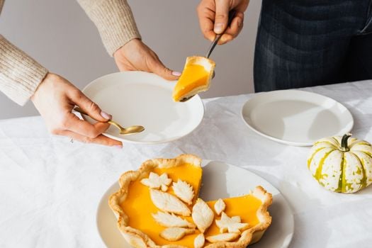 Elegant pumpkin pie slice being served with white plates and decorative gourd on a table.