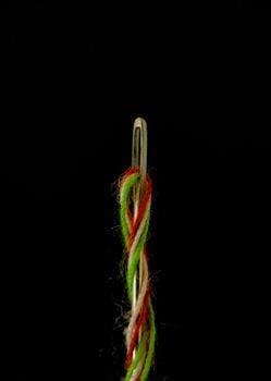 Extreme close-up of a sewing needle with colorful threads. Ideal for creative and crafting themes.