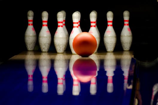 A striking close-up of a bowling ball approaching pins in a bowling alley.